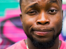 a young black male with bright clothing and a quizzical/skeptical look